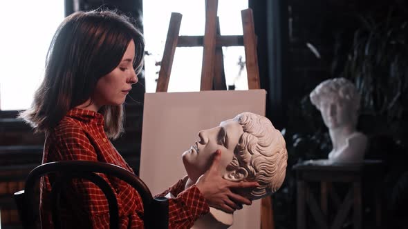 A Young Woman in Art Workshop Holding a Greek Head Sculpture