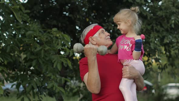 Granddaughter and Grandfather Doing Fitness Exercises with Dumbbells. Senior Man with Child Kid Girl