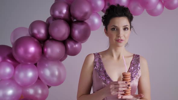 Woman in a Purple Dress Stands on the Background of Balloons