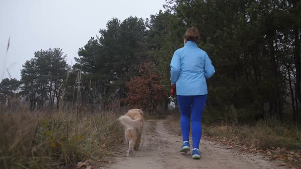 Female Trail Runner with Pet Jogging in the Wood