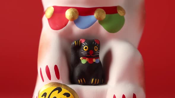 Maneki-neko, lucky cat with a small black kitten close up
