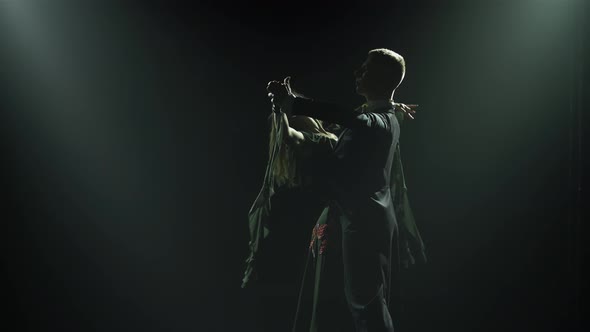 In the Dark Among the Smoke a Silhouette of a Couple is Seen Dancing Elements of a Waltz