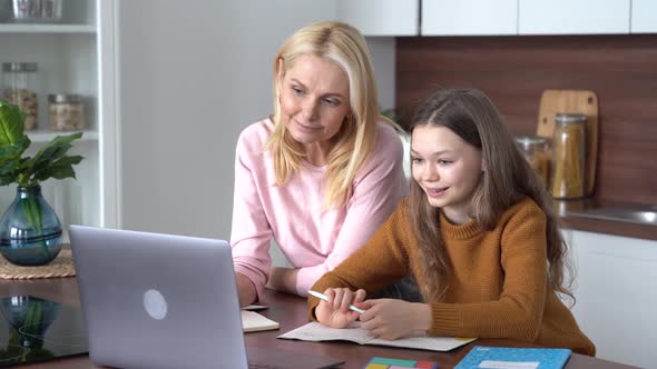 Teen Child Daughter Studying at Home in Kitchen with Mom
