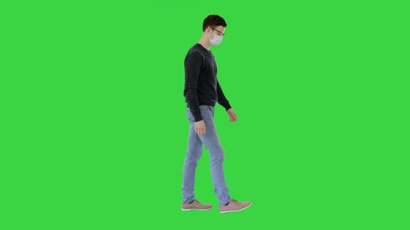 Young Handsome Man Walking with Medical Mask on on a Green Screen, Chroma Key.