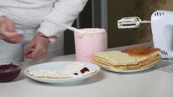 A Woman Puts Cherry Filling On Biscuit Cakes Smeared With Cream