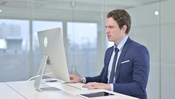 Tired Young Businessman Having Back Pain in Modern Office 