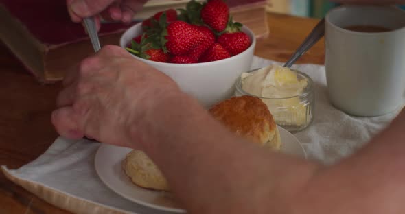A Person Preparing Scones, Cream and Jam in Cornwall on a Table. Delicious Cornish Food with a Cup o