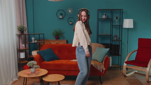 Pretty Caucasian Young Woman in Headphones Listening Music Dancing Singing in Living Room at Home