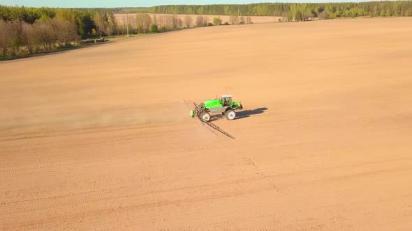 Tractor Spraying a Field with Sprayer Herbicides and Pesticides at Sunset