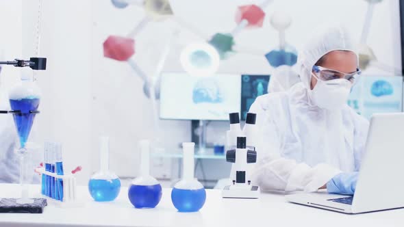 Female Scientist Working in a Modern Laboratory with Reagent in Test Tubes with Blue Liquid and