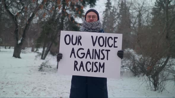 Male Protester Holding a Poster Our Voice Against Racism. Promoting Equality