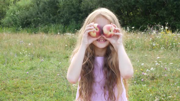 Attractive Young Girl Smiling into the Camera Holding Peaches.