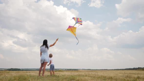 Happy Family Mom and Son Playing with Flying Kite on Meadow in Beautiful Sunny Day Blue Sky