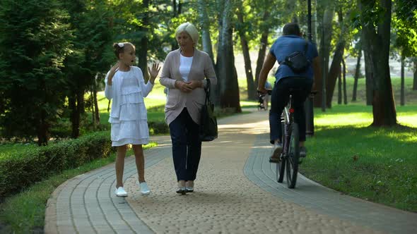 Happy Girl Telling Stories to Grandmother Walking in Park, Trusting Relations