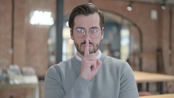 Portrait of Young Man Showing Quiet Sign By Finger on Lips