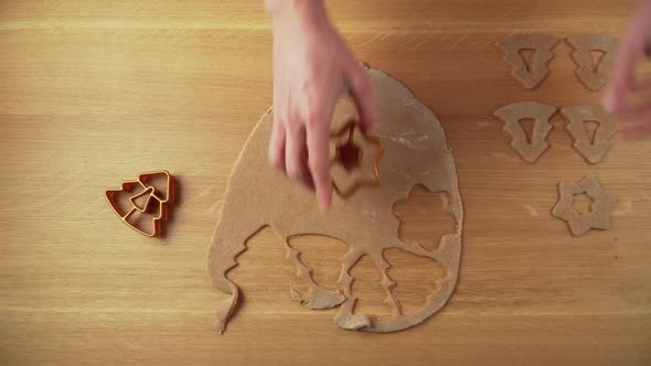 Making christmas shapes from gingerbread dough on a wooden table topdown video