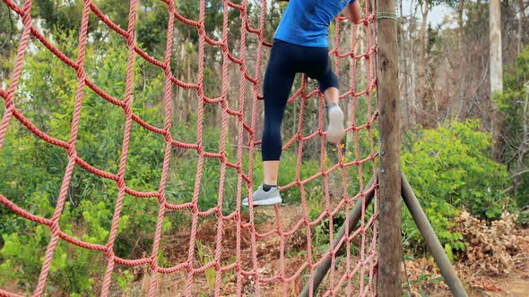 Fit woman climbing a net during obstacle course