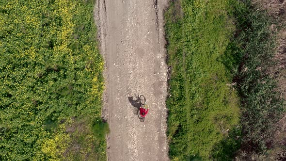 a Girl in a Red Jacket Rides a Bicycle in the Countryside