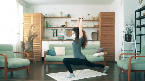 A Girl in Medical Mask Stretches at Home