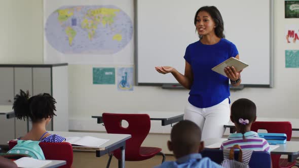 Portrait of mixed race female teacher standing in classroom asking questions during lesson