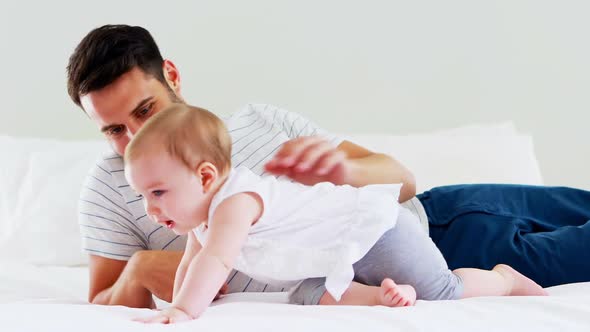 Father playing with his baby girl in bedroom