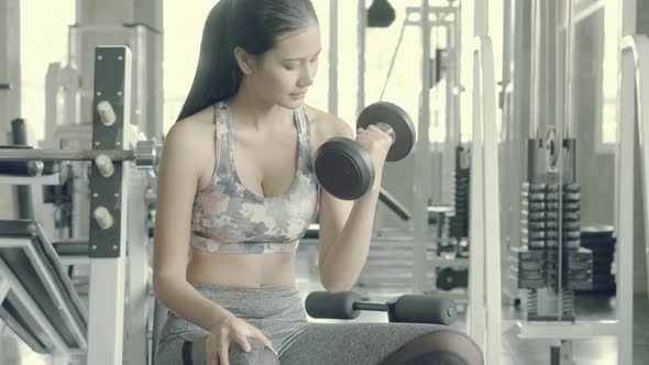 Young asian woman bodyweight with lifting dumbbell at fitness.