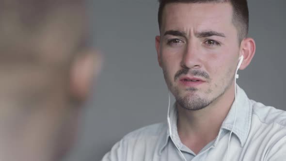 Man in Headphones Talking to Colleague