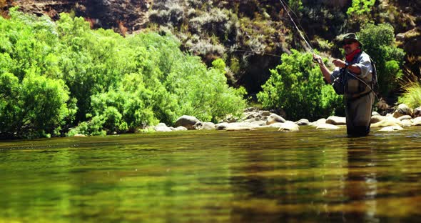 Fisherman fly fishing in river