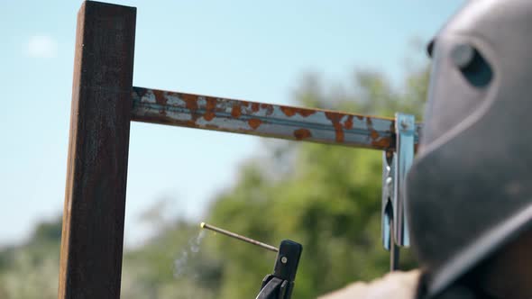 Close View Worker in Welding Mask Connects Parts of Fence