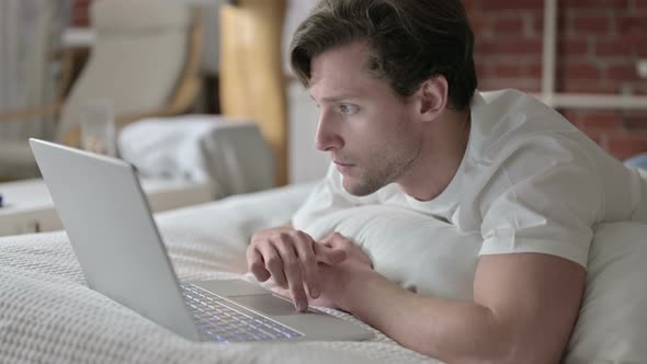 Ambitious Young Man Using Laptop in Bed