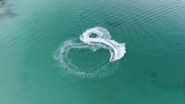 Jetskier In Full Speed Performing A Circle And Exhibition On The Crystal Clear Water And Leaving A W