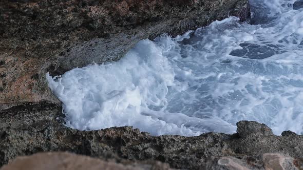 Waves crashing against sea cliff. Detail shot in slow motion of the foam