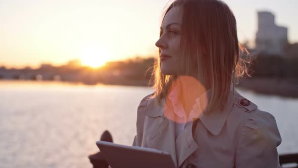 Woman Typing on Tablet at Sunset