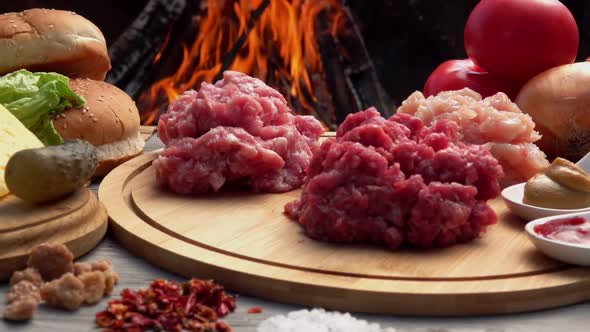 Chicken, Beef and Pork Minced Meat on the Board on the Background of a Fire