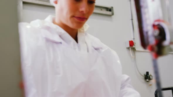 Female butcher cutting raw meat on a band saw machine