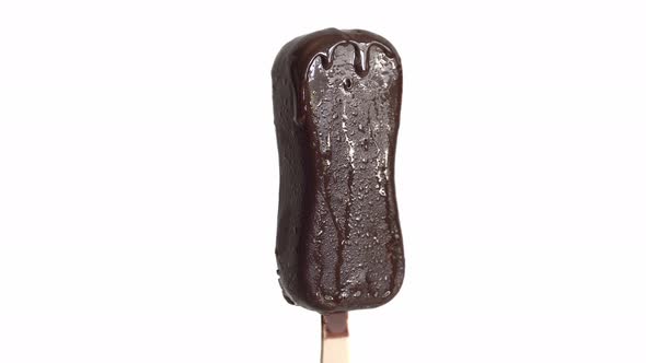 White Ice Cream Melts On A Wooden Stick. The Chocolate Flows Down.