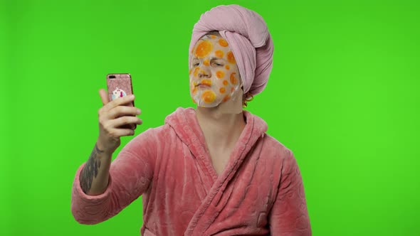 Young Man in Bathrobe with Face Mask Using Mobile Phone for Video Call