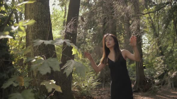 Medium shot of Beautiful asian woman in black Exploring sunny forest, Slowmo