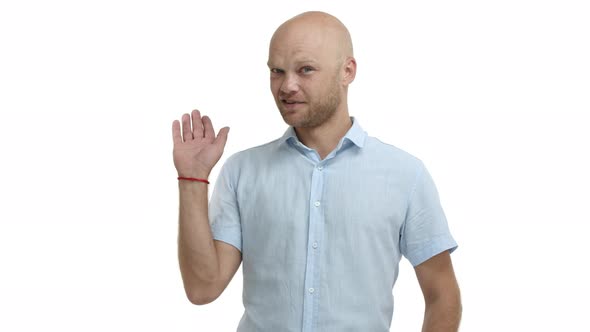 Middleaged Bald Man with Beard Wearing Blue Shirt Waving Away in No Big Deal Gesture Express Humble