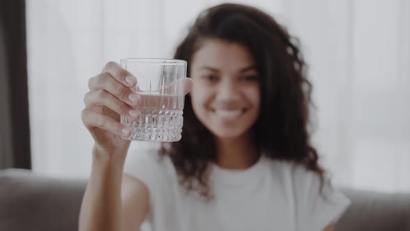 Smiling Young African Woman Holding Glass of Fresh Clear Purified Potable Water Offer to Drink