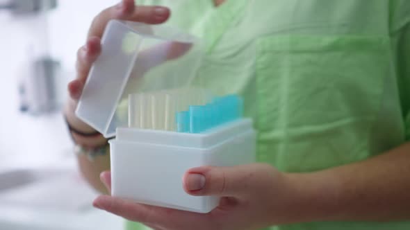 Closeup Female Hands Opening Box with Lab Tubes in Medical Laboratory