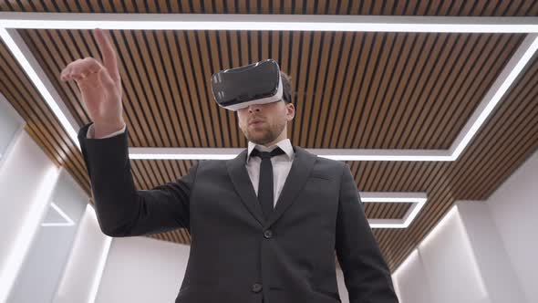 Bottom Angle View of Creative Confident Caucasian Young Man IN VR Headset Moving Hands Standing in