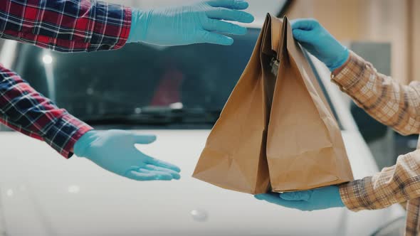 Messenger Transfers Bags of Groceries to the Recipient Near the Delivery Service Van