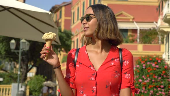 A woman eating gelato ice cream while traveling in a luxury resort town in Italy, Europe.