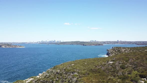 Aerial flight over the rugged coastline of North Head, Manly. With Sydney in the distance