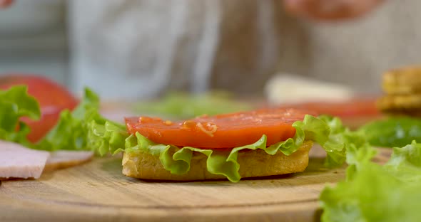 Female Chef in the Kitchen of the House Collects a Sandwich