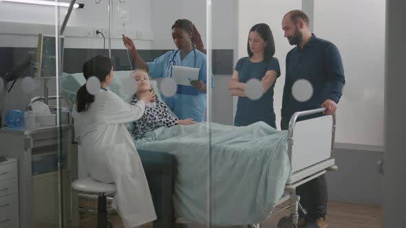 Pediatric Doctor Examining Breathing Sickness Symptoms While African American Nurse Checking IV Drip