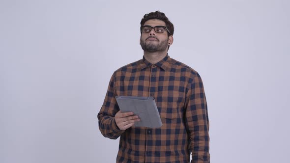 Stressed Young Indian Hipster Man Using Digital Tablet and Getting Bad News