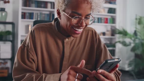 Young Delighted African American Woman Rejoices at Seeing Good News on Phone