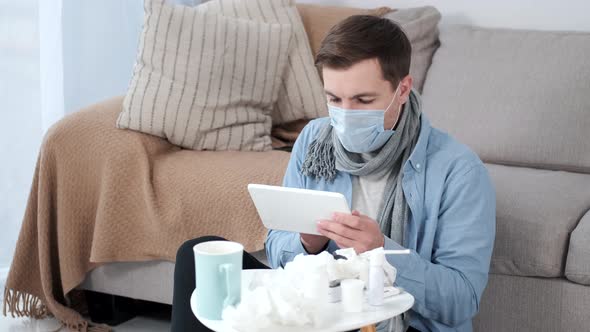 Very Sick Young Man with Digital Tablet Sitting on Couch